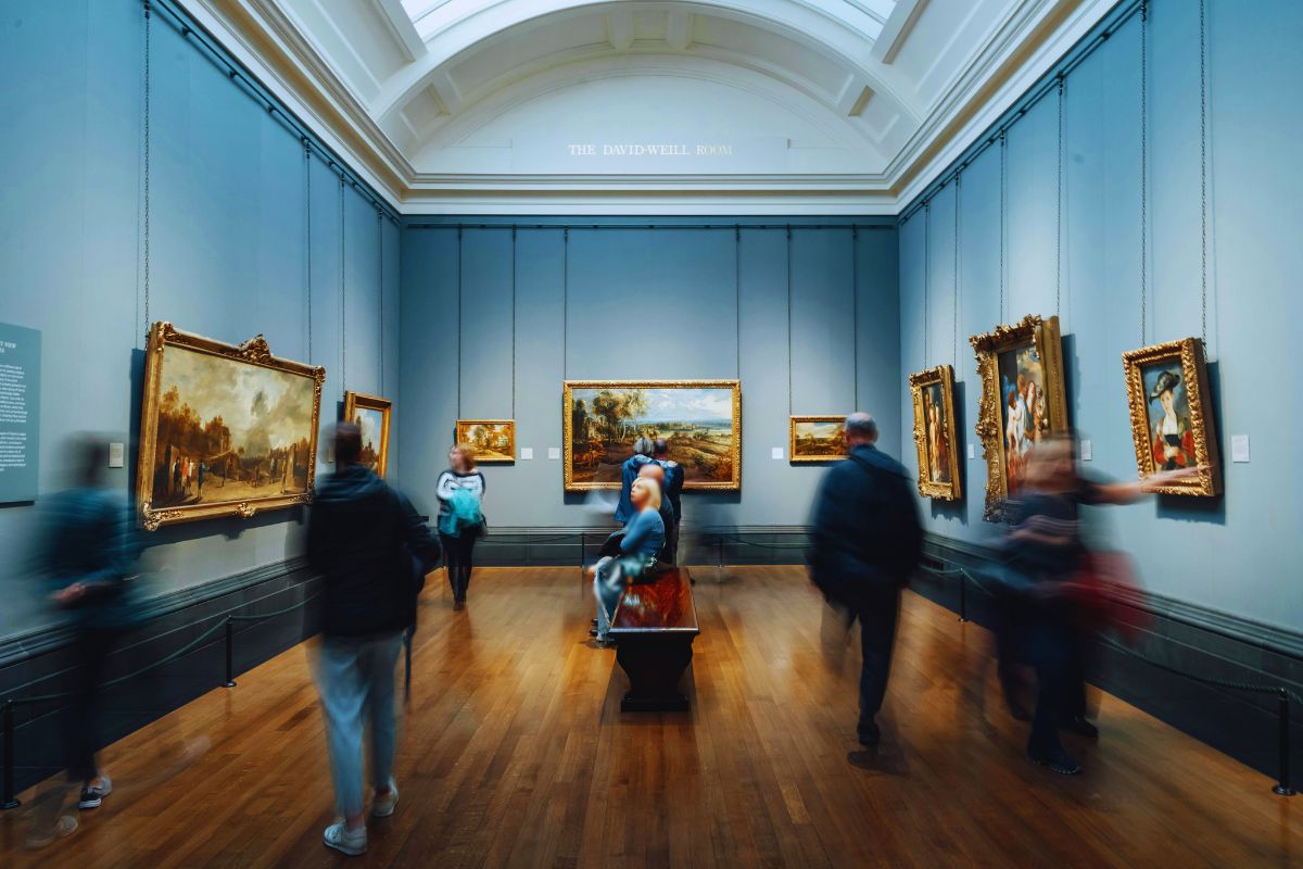 Na imagem h&aacute; pessoas dentro de um museu olhando as obras de artes, demostrando o que &eacute; o turismo cultural