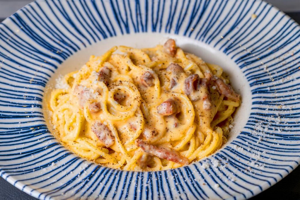 Na imagem está o prato carbonara que é uma típica comida típica que o turista encontra numa viagem à Itália