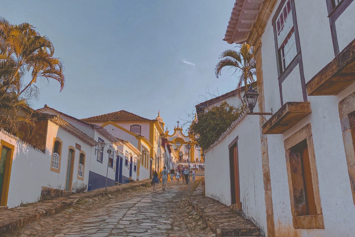 Ladeira de pedras com casarios coloniais e igreja ao fundo em Tiradentes, uma das cidades históricas de Minas Gerais mais visitadas do Brasil