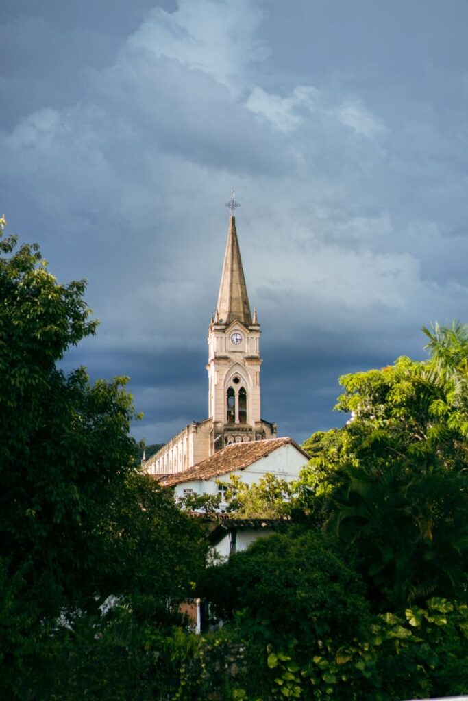 Torre de igreja histórica emoldurada pela vegetação em Goiás Velho, destino de turismo histórico no Centro-Oeste brasileiro